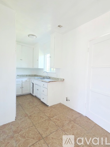 A kitchen with white cabinets and a tiled floor.