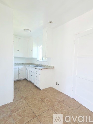 A kitchen with white cabinets and a tiled floor.