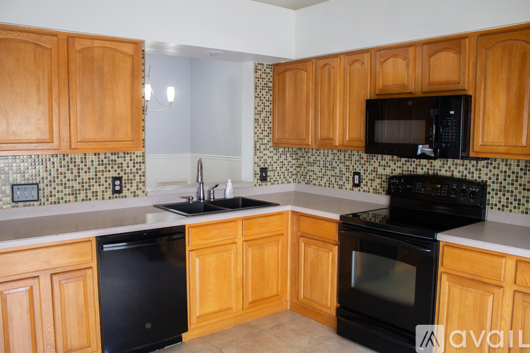 A kitchen with wooden cabinets and black appliances.