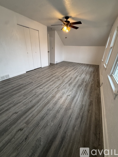 A room with a ceiling fan and wooden flooring.