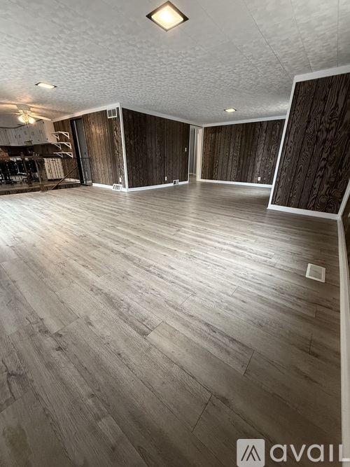 A spacious room with wooden flooring and a white ceiling.