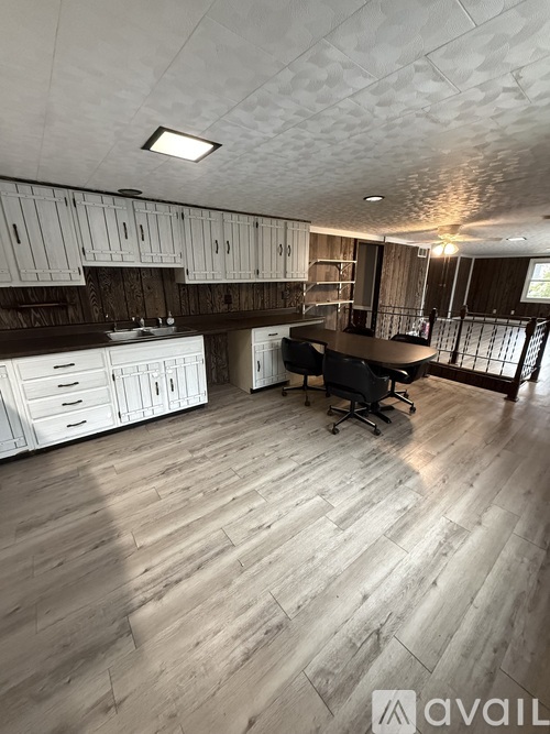 A kitchen with white cabinets and a wooden floor.