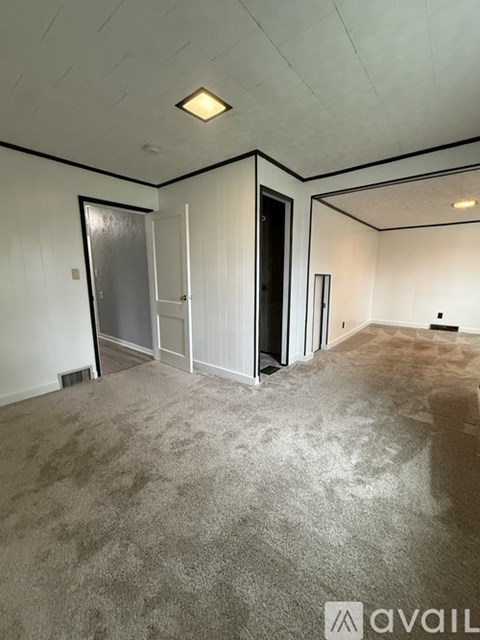 A room with a carpeted floor and a door on the left side.