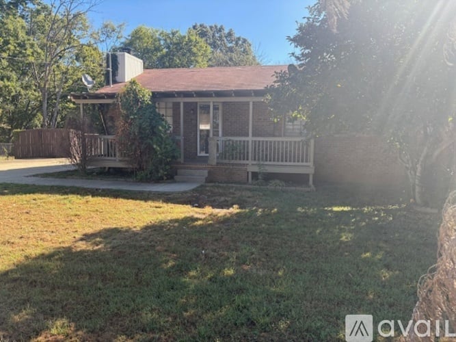A house with a porch and a tree in front of it.