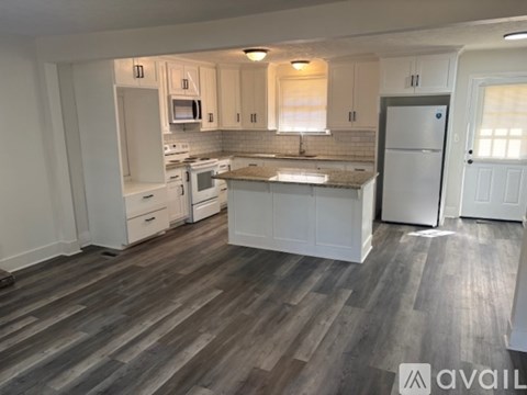 A kitchen with white cabinets and a wooden floor.