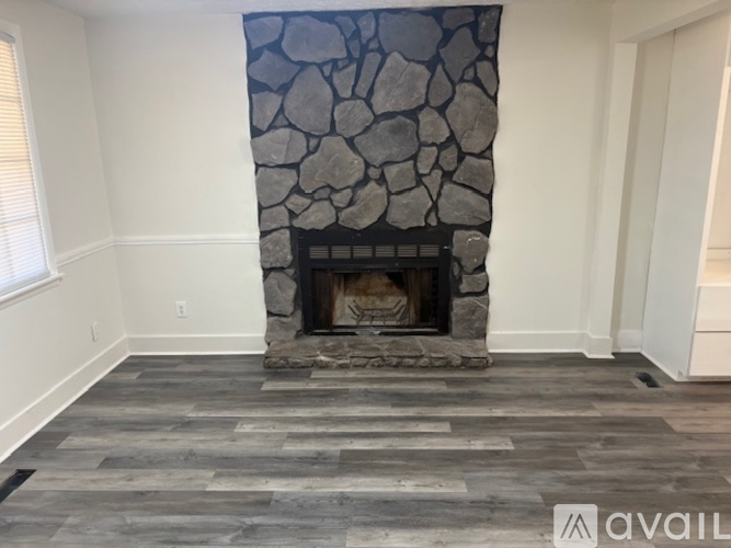A stone fireplace in a room with wooden flooring.
