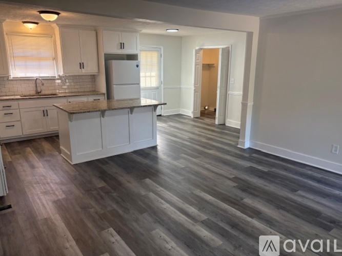 A kitchen with white cabinets and a wooden floor.