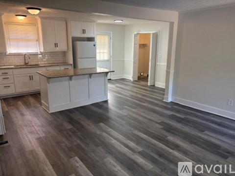 A kitchen with white cabinets and a wooden floor.