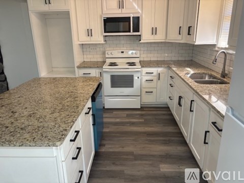 A kitchen with granite countertops and white cabinets.