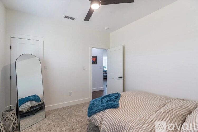 A bedroom with a bed, dresser, mirror and a ceiling fan.
