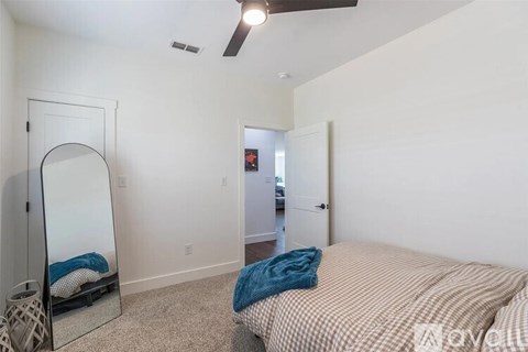 A bedroom with a bed, dresser, mirror and a ceiling fan.