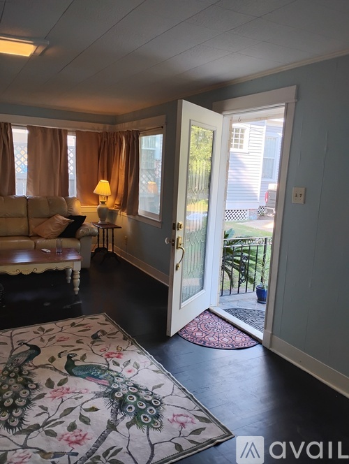 A living room with a couch, a lamp, and a door leading to a backyard.