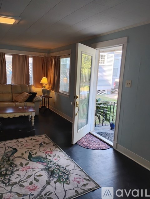 A living room with a couch, a lamp, and a door leading to a backyard.