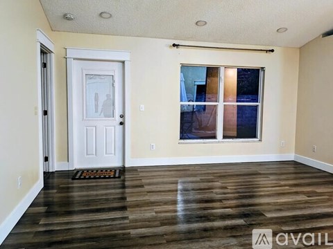 A room with a white door and a window with a view of a building outside.