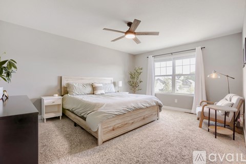 A bedroom with a large bed, a chair, and a ceiling fan.