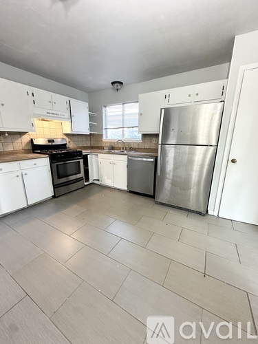 A kitchen with white cabinets and a tile floor.