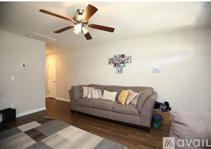 A living room with a grey couch and a ceiling fan.