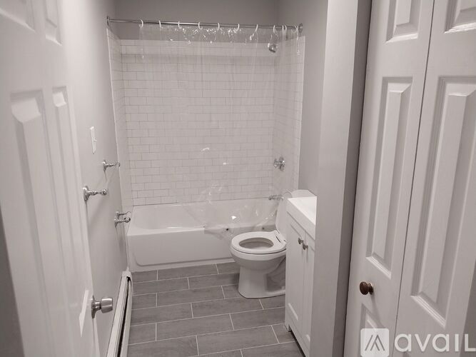 A white bathroom with a toilet, tub, and shower.