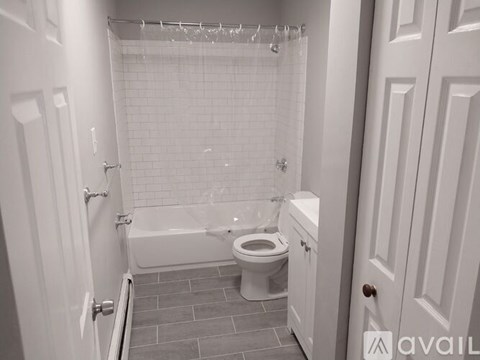 A white bathroom with a toilet, tub, and shower.