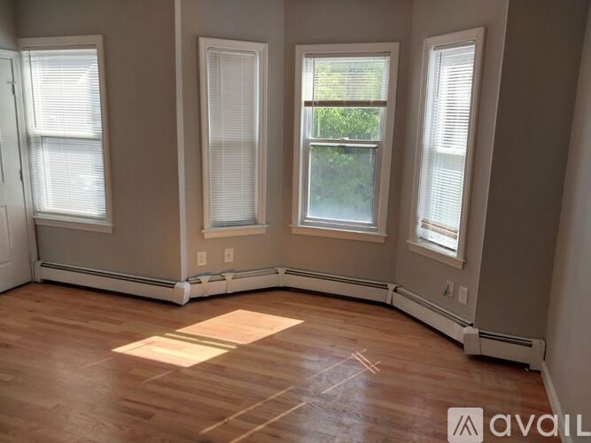 A room with three windows and wooden flooring.