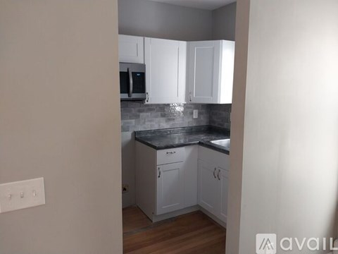 A kitchen with white cabinets and a black countertop.
