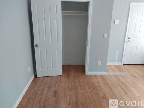 A room with a white door and wooden flooring.