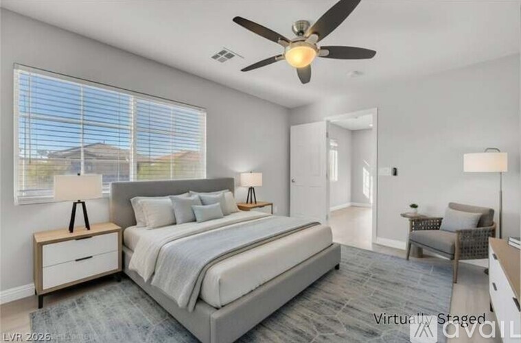 A bedroom with a large bed, a ceiling fan, and a view of the outdoors through the window.