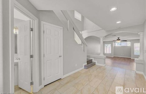 A spacious room with a staircase and a ceiling fan.