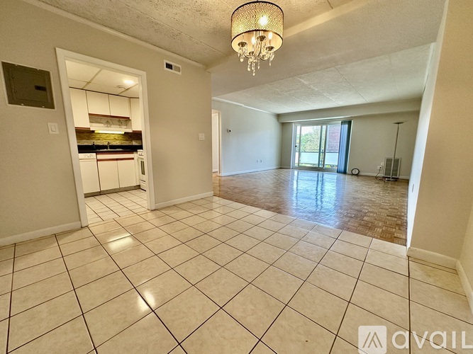 A spacious room with a chandelier and tiled flooring.