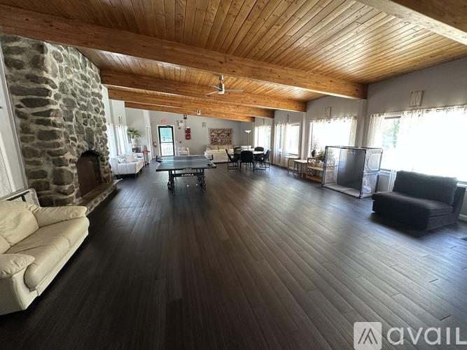 A spacious living room with wooden floors and a stone wall.