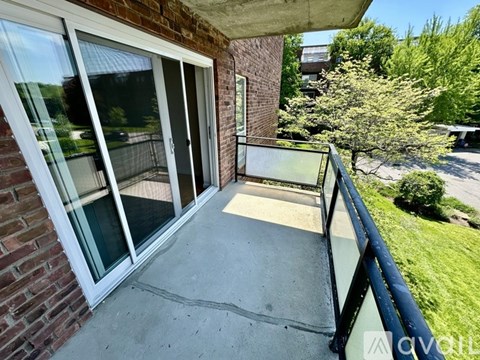 A balcony with a glass railing and a brick wall.