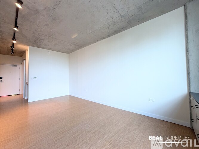 A spacious room with a wooden floor and white walls.
