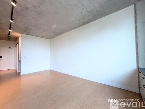 A spacious room with a wooden floor and white walls.
