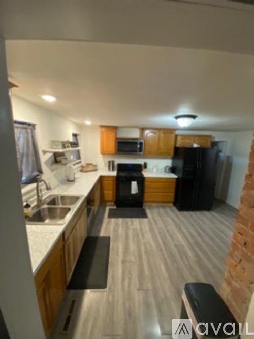 A kitchen with wooden cabinets and a black fridge.