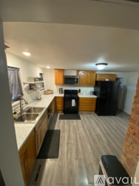A kitchen with wooden cabinets and a black fridge.
