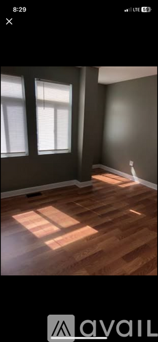 A room with wooden flooring and two windows.