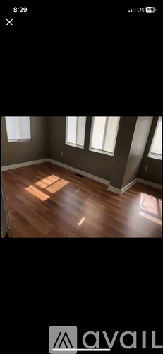 A room with wooden flooring and three windows.