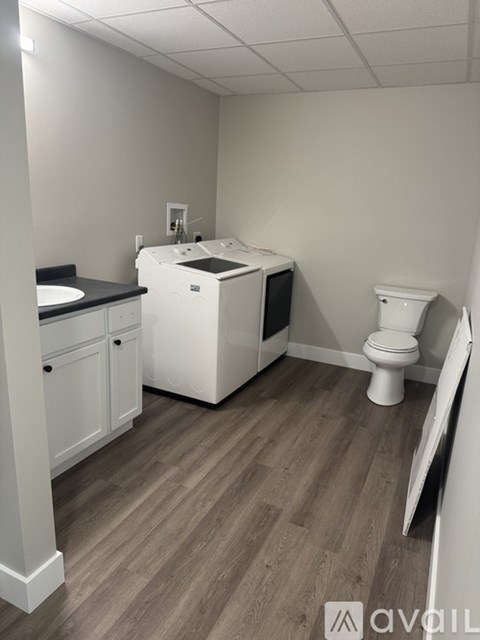 A bathroom with a toilet, sink, and cabinet.