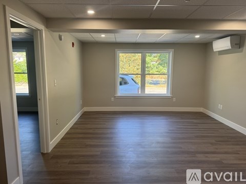 A room with wooden floors and a window overlooking a parking lot.