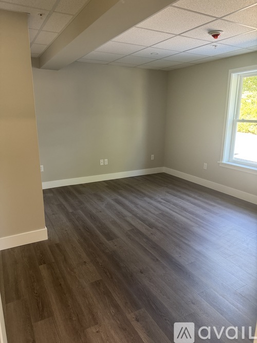 A room with wooden flooring and a window on the wall.
