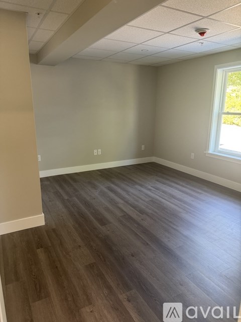 A room with wooden flooring and a window on the wall.