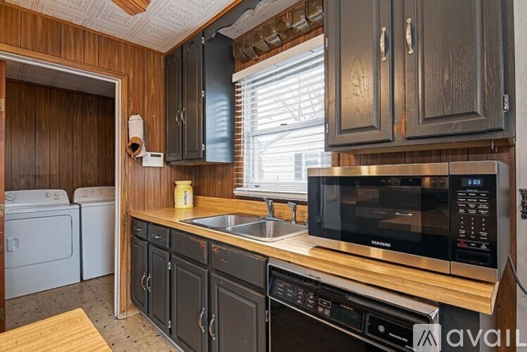 A kitchen with wooden cabinets and a black microwave.