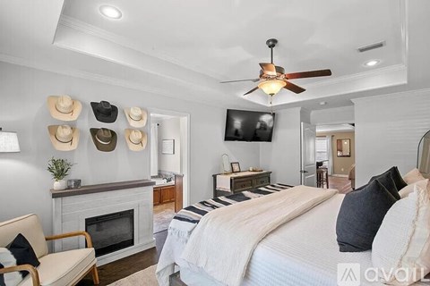 A bedroom with a fireplace and a bed with a white comforter.