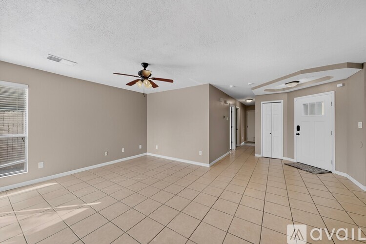 A spacious room with a ceiling fan and tiled flooring.