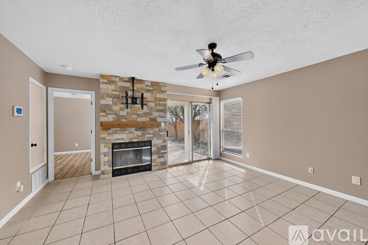 A living room with a stone fireplace and a ceiling fan.