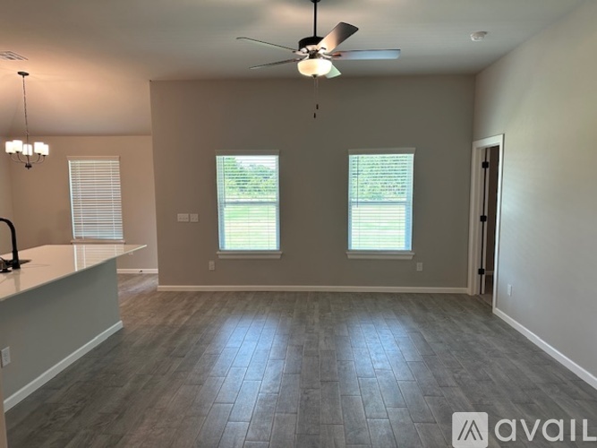 A spacious room with a ceiling fan and two windows.