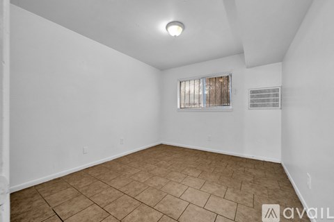 A room with a tiled floor and a window with blinds.