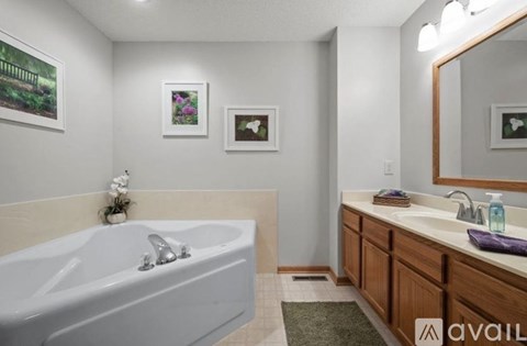 A bathroom with a white tub and wooden cabinets.
