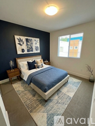 A bedroom with a bed, nightstand, and a window.