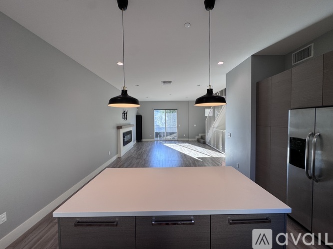 A kitchen with a long counter and a refrigerator on the right side.